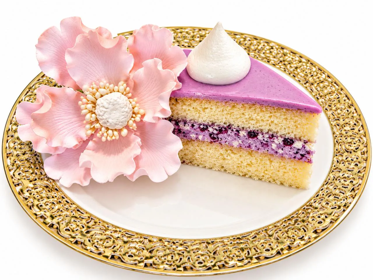 A slice of cake with a sugar flower on a gold plate